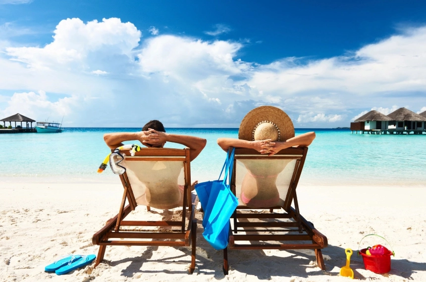 Two people sitting on lounge chairs at the beach